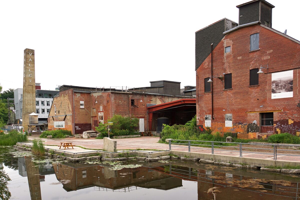 The old red-brick kiln buildings and tall brick chimney of the Don Valley Brick Works beside a lily pond
