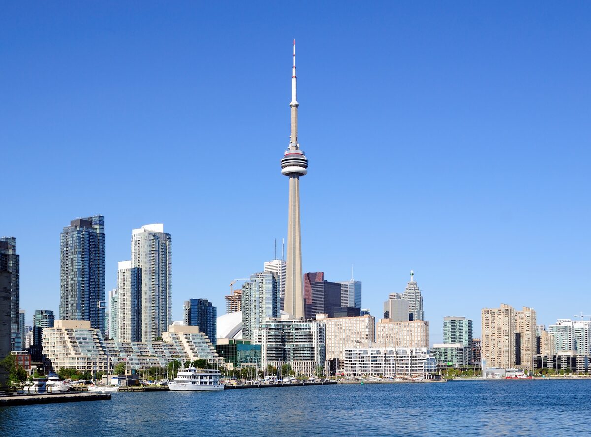 The CN Tower and waterfront condo towers seen across the blue water of Toronto Harbour on a clear day