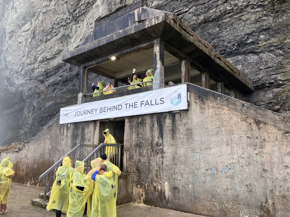 The Journey Behind the Falls observation deck cut into the gorge wall, with visitors in yellow ponchos
