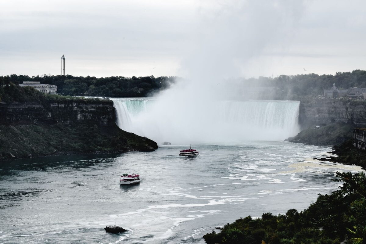 Two tour boats on the churning water below Horseshoe Falls, with mist rising over the gorge