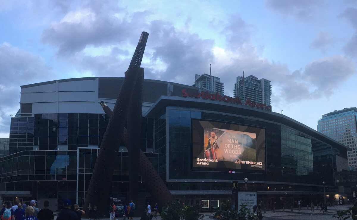 The glass front of Scotiabank Arena at dusk with a large screen on its facade