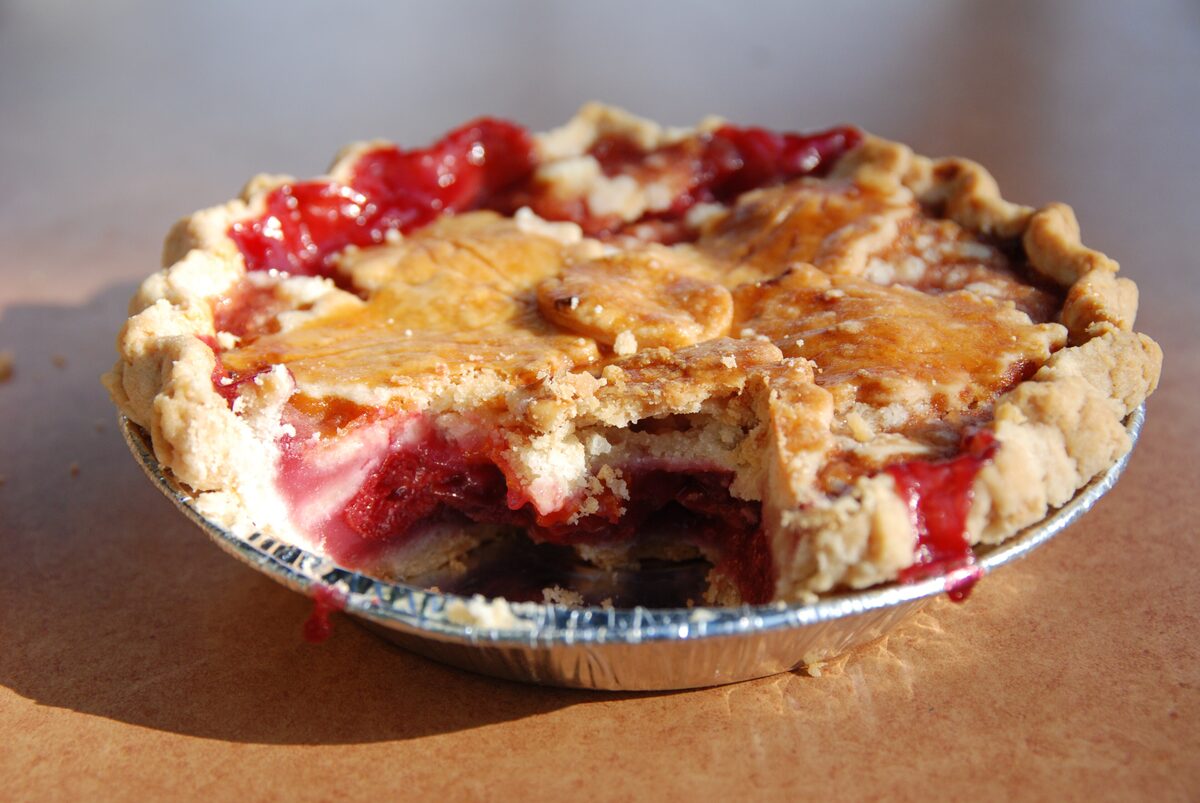 A cherry pie with a golden lattice crust and a slice cut out, baked by Wanda's Pie in the Sky