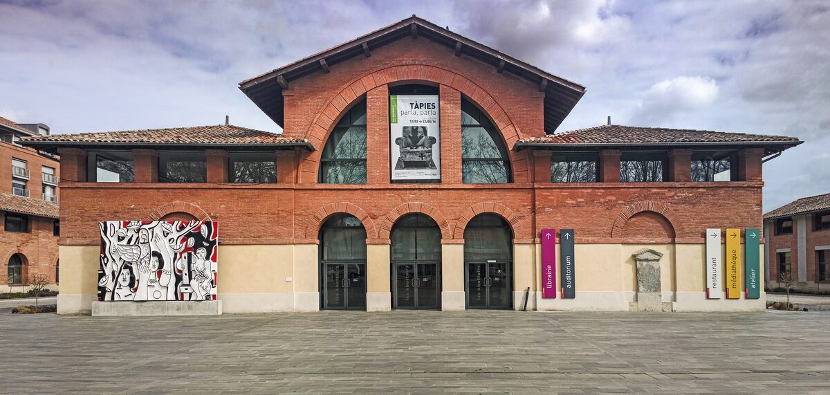 The brick facade of Les Abattoirs, the contemporary art museum in Toulouse, with arched windows