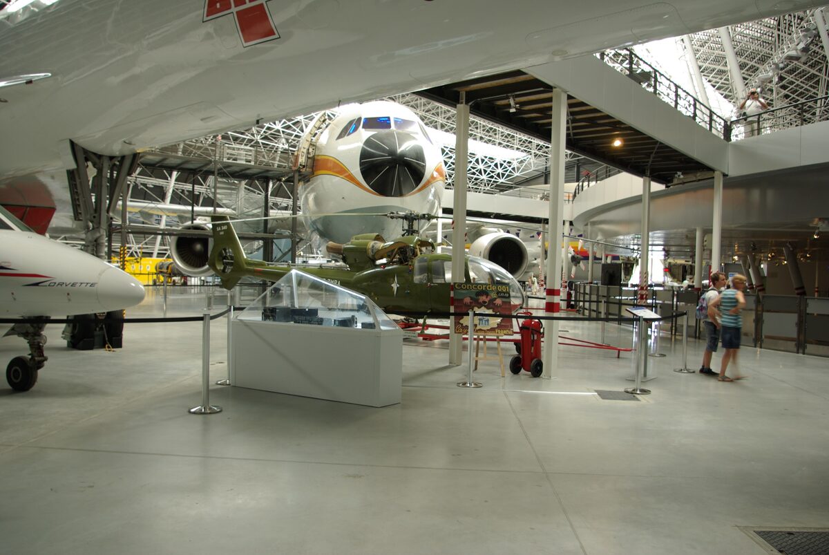 Inside the Aeroscopia hall, aircraft on display under a high roof with visitors on the floor