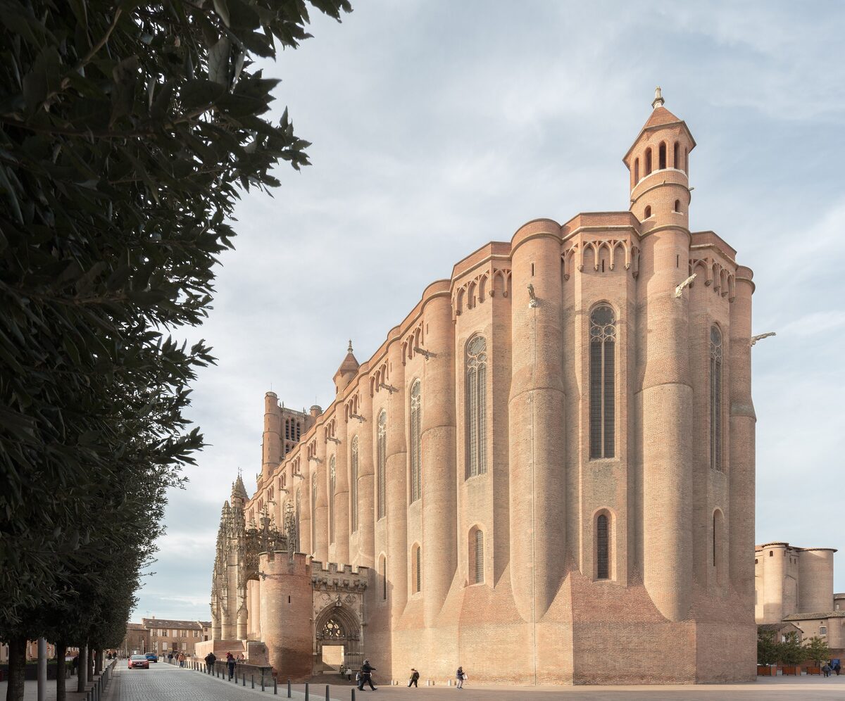 The brick walls and tower of Sainte-Cécile cathedral in Albi, with a tree on the left