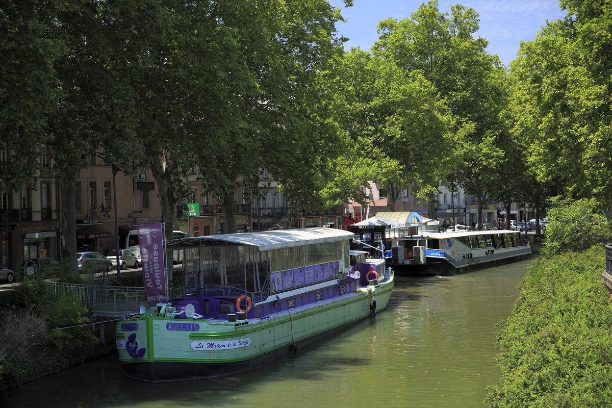 Moored boats along the Canal du Midi in Toulouse, with trees on both banks