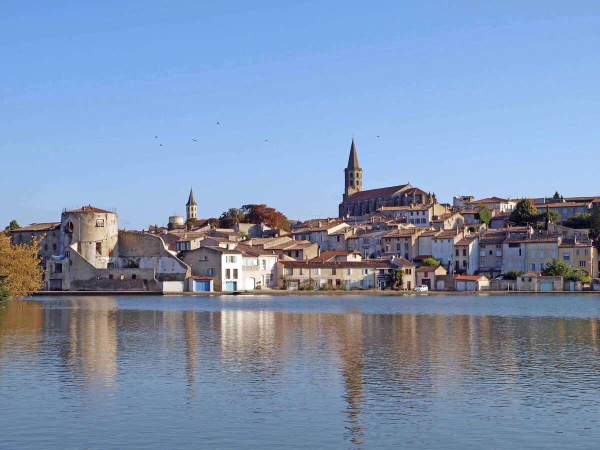 Houses and church spires of Castelnaudary reflected in the still water of the Grand Bassin on the Canal du Midi