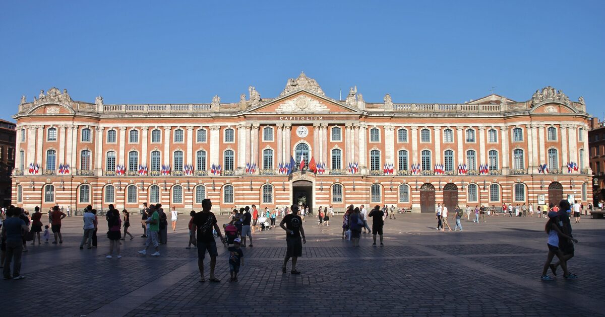 The stone and pink-brick facade of the Capitole across Place du Capitole in Toulouse on a clear day