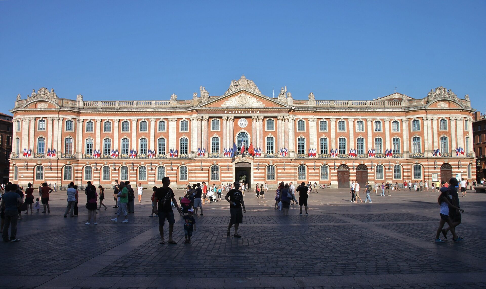 The stone and pink-brick facade of the Capitole across Place du Capitole in Toulouse on a clear day