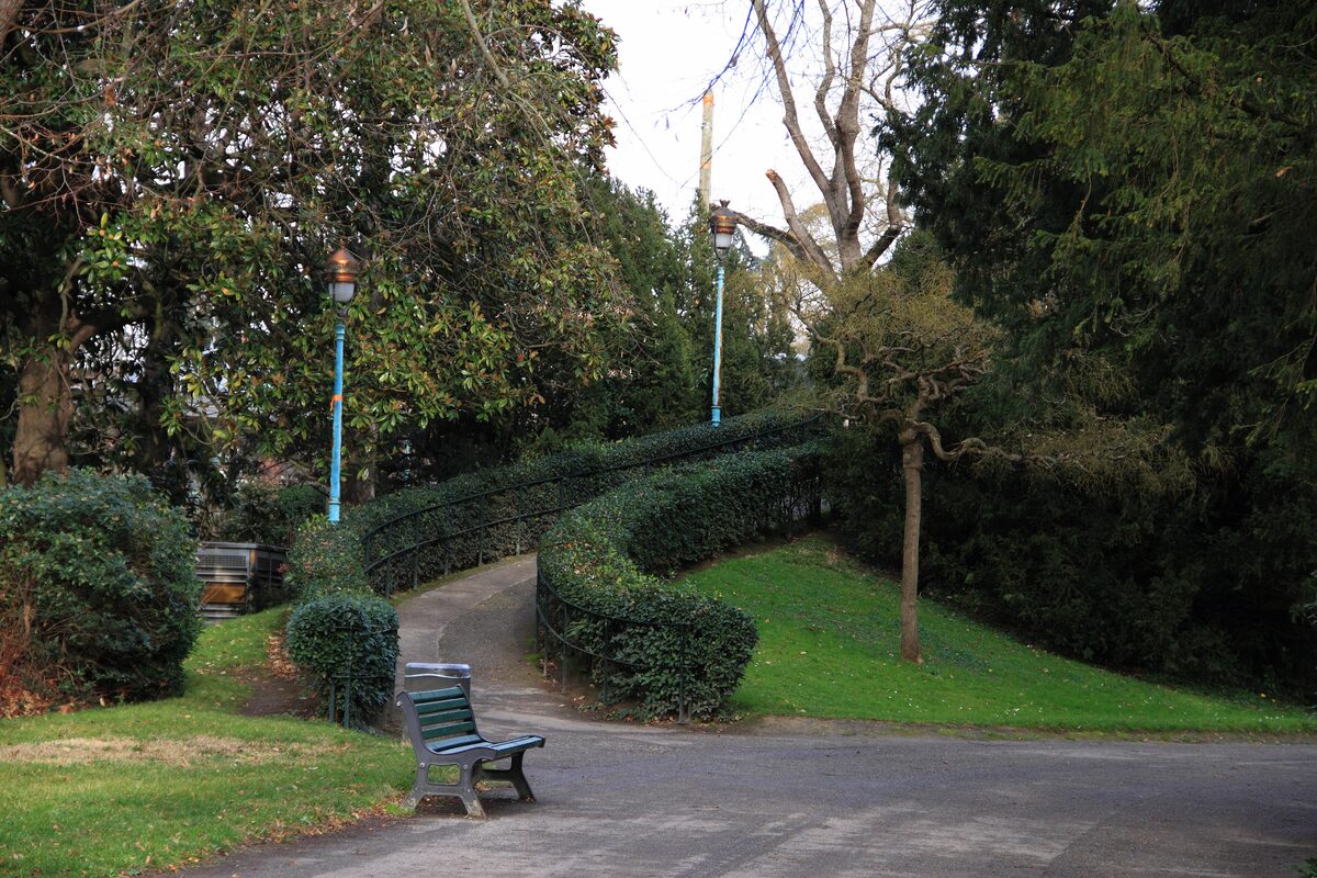 A winding path between clipped hedges and park benches in the Jardin des Plantes in Toulouse
