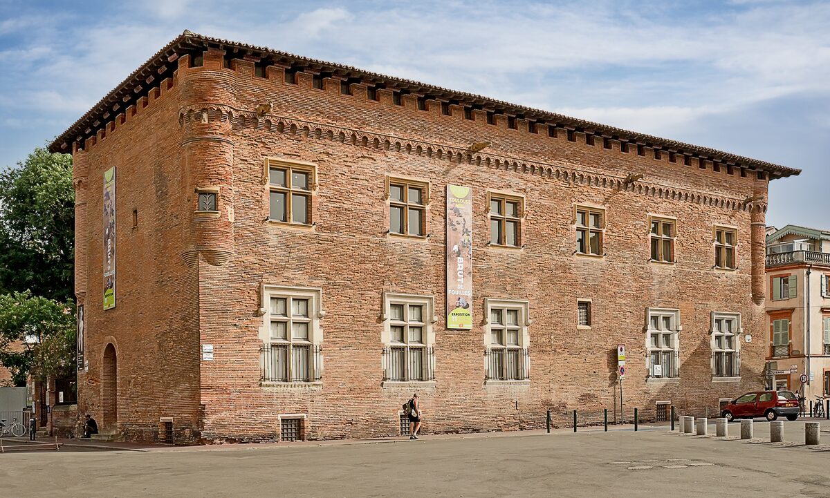 The brick facade of the Musée Saint-Raymond on Place Saint-Sernin, a Renaissance building with a decorated cornice and corner turrets