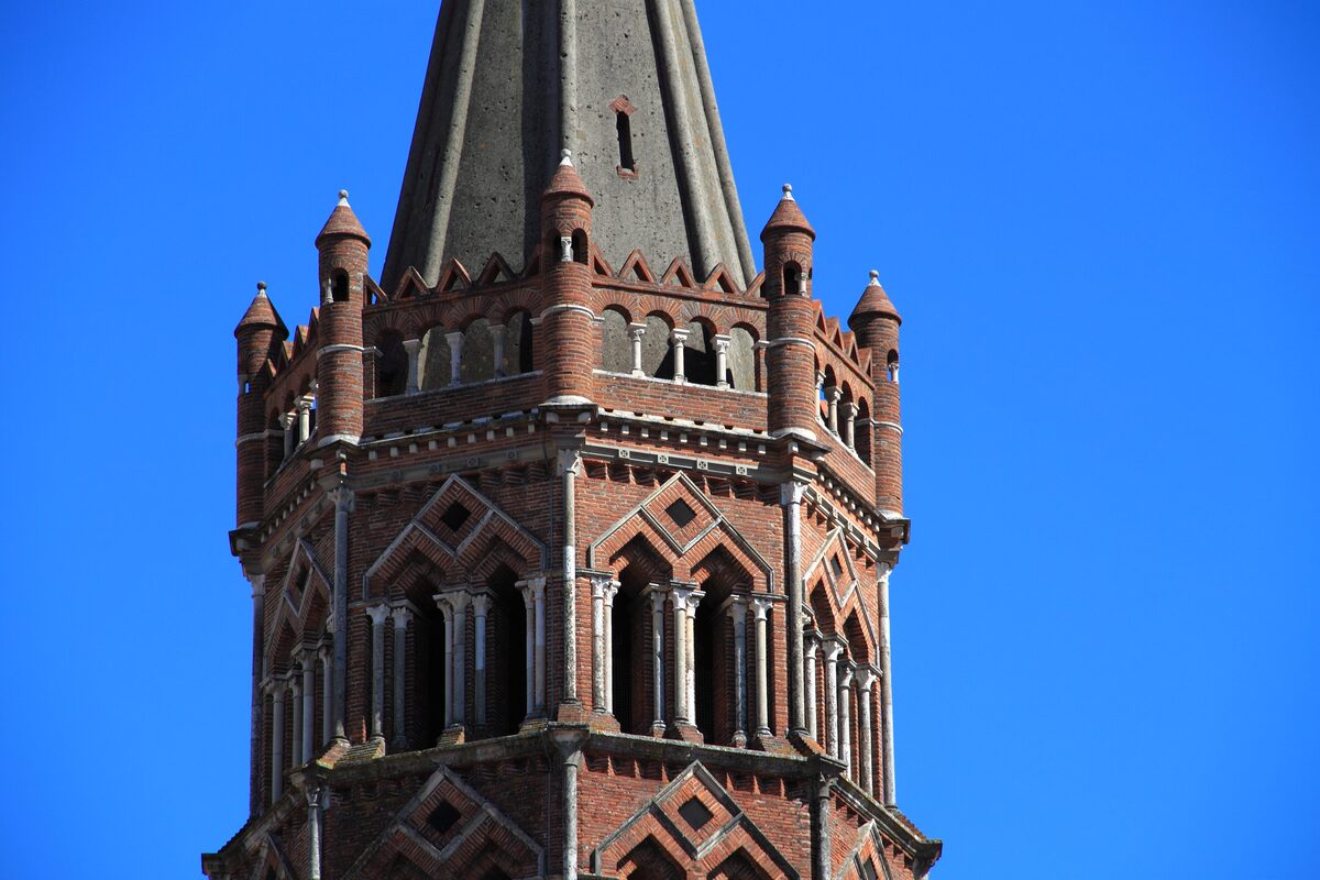 The brick bell tower of Saint-Sernin with tiered turrets against a clear blue sky