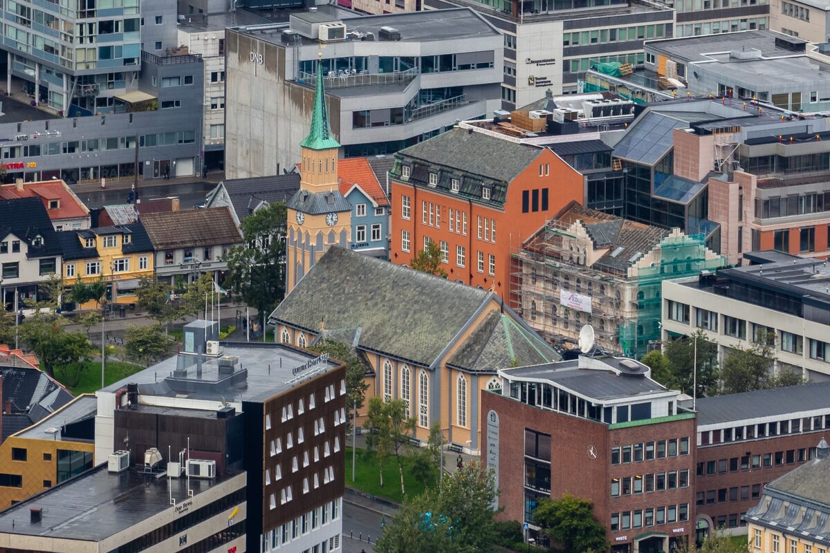 Tromsø's pale wooden cathedral with its green spire among the rooftops of the town center, seen from above