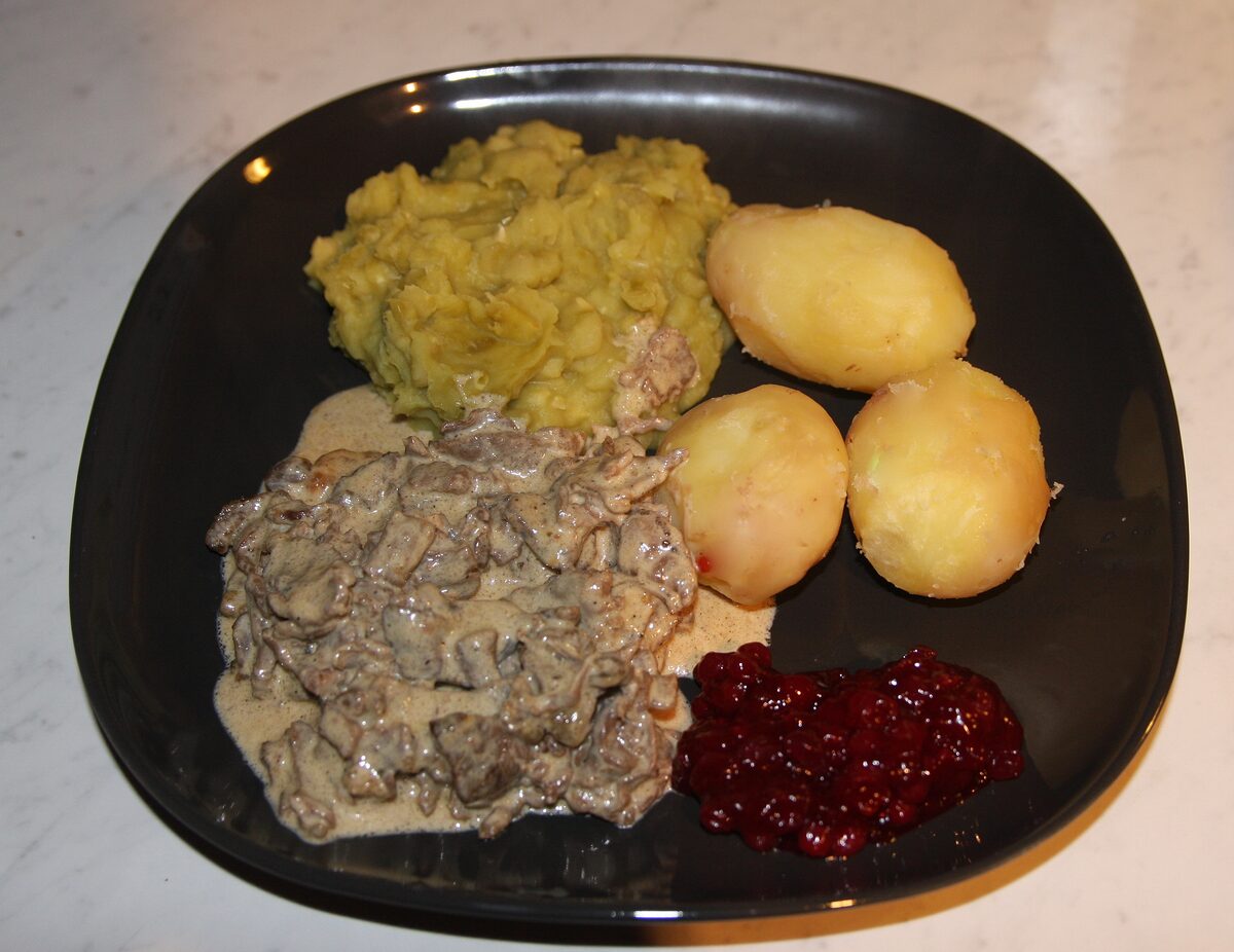 A plate of finnbiff, sautéed reindeer in cream sauce, with mashed peas, boiled potatoes and lingonberries