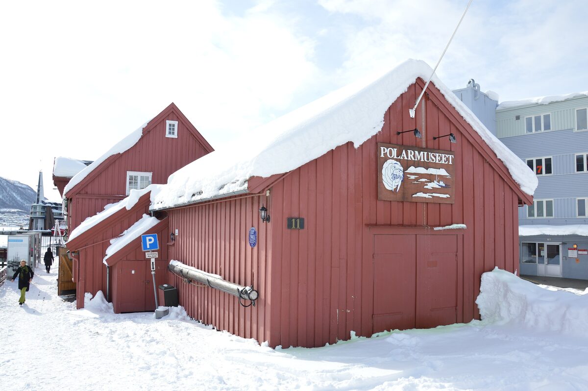 The red wooden warehouse of the Polar Museum in Tromsø covered in deep snow