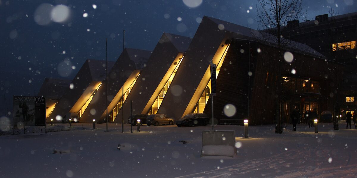The Polaria building at night, shaped like ice floes tipped against each other, with snow falling