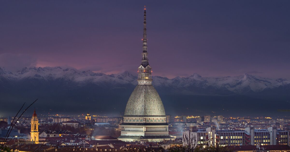 The Mole Antonelliana rising above the rooftops of Turin with the snowy Alps behind it