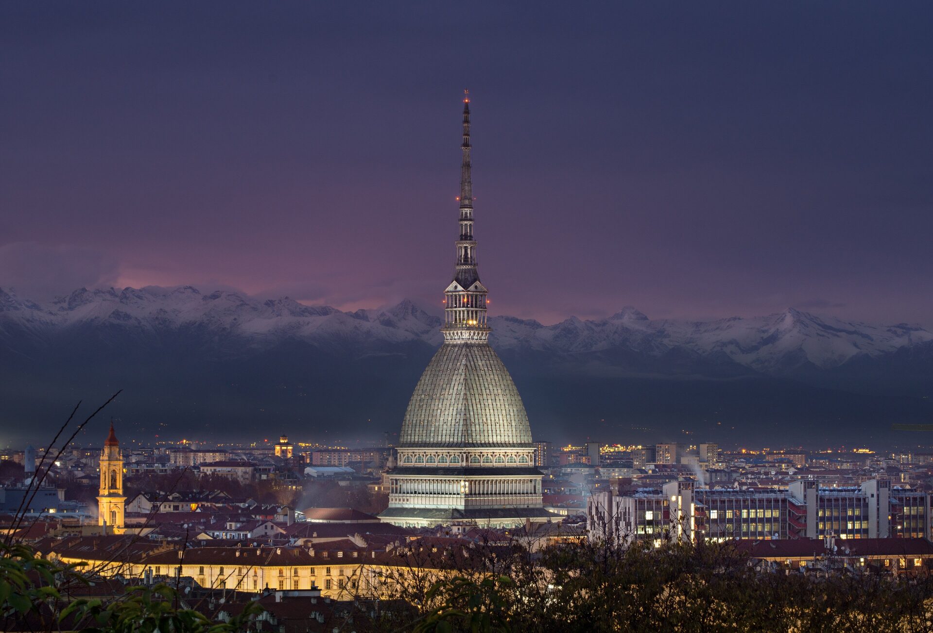 The Mole Antonelliana rising above the rooftops of Turin with the snowy Alps behind it