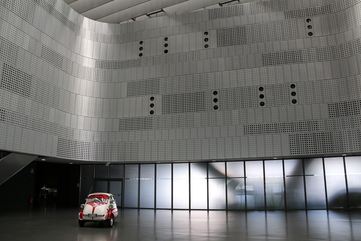 A small vintage car alone in the vast hall of the car museum