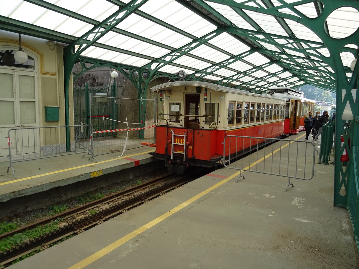 The red vintage rack tram in Sassi station under a green iron canopy