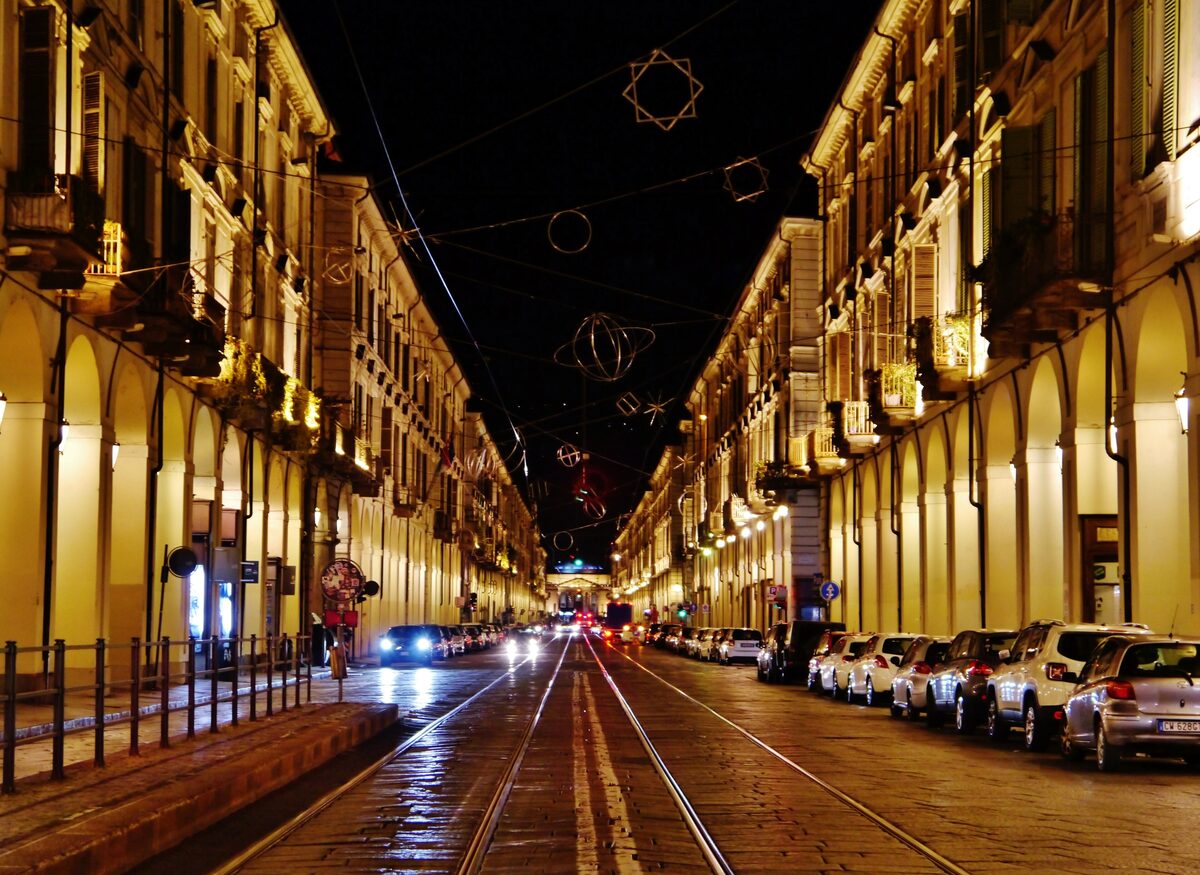 Via Po at night, its arcades lit and a tram track down the middle