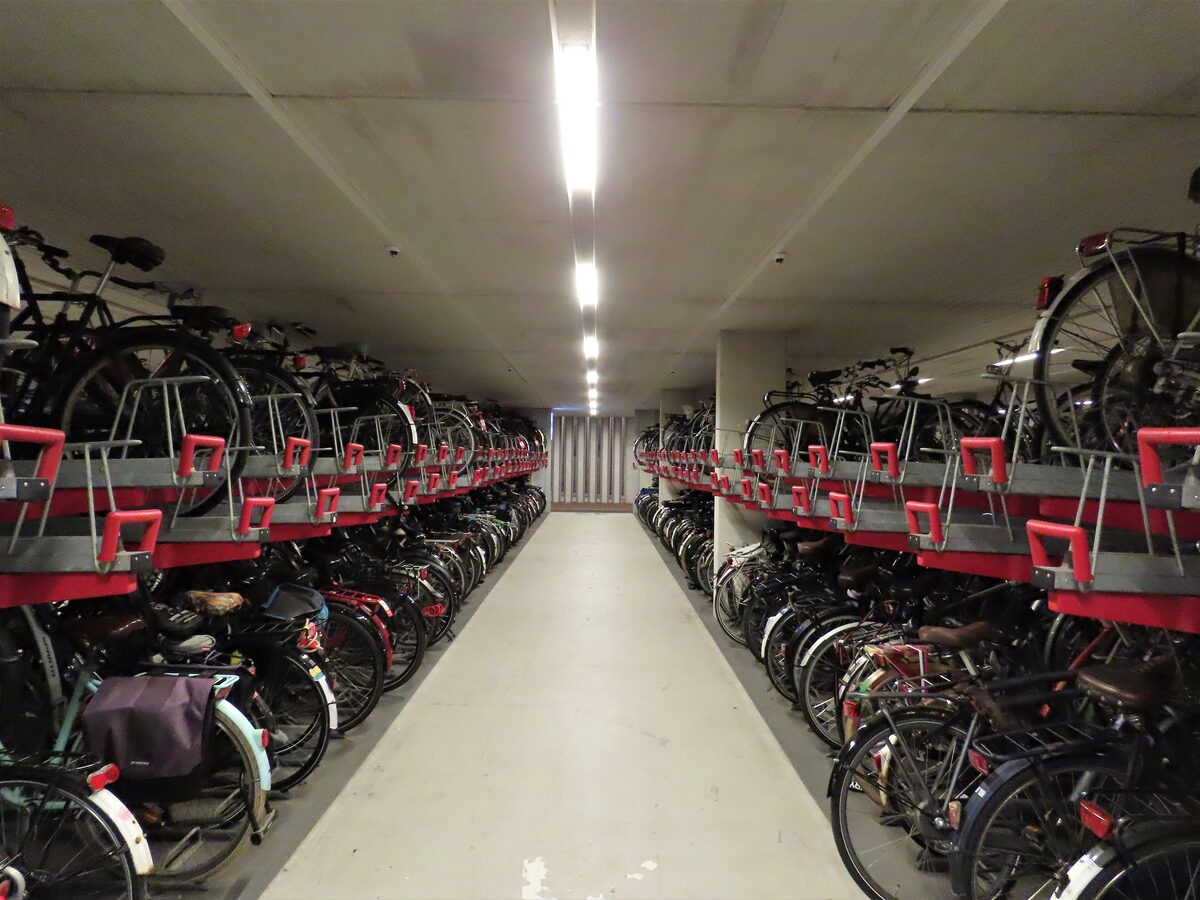 Long rows of bicycles on two-level red and gray racks in the underground bike parking at Utrecht station