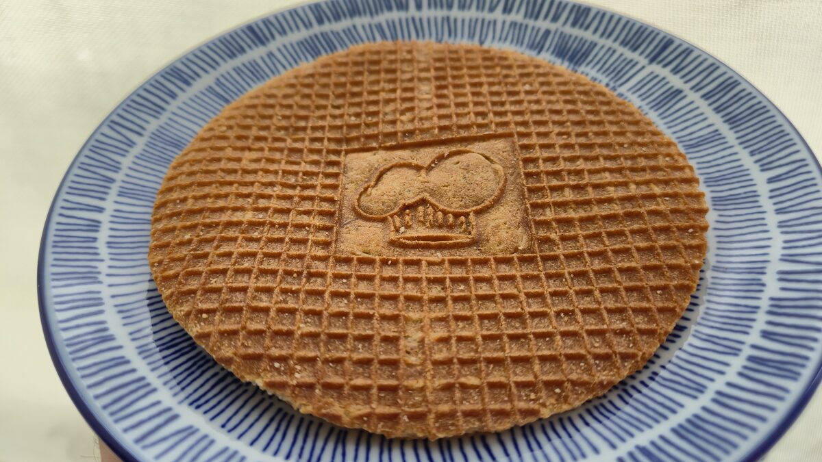 A single stroopwafel with a stamped center on a blue and white striped plate