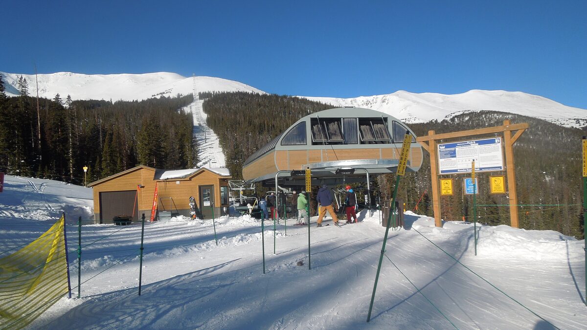 The bottom station of the Kensho SuperChair on snowy Breckenridge slopes under a blue sky