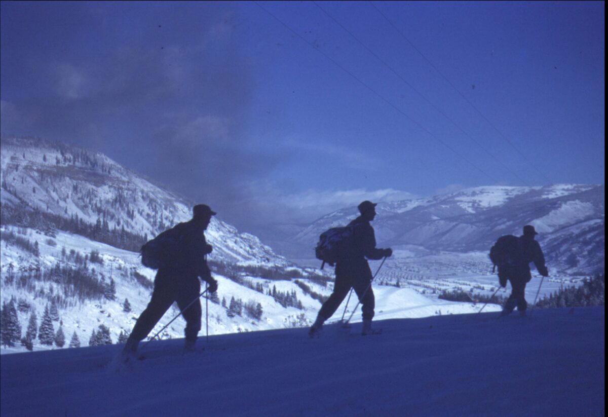 Three 10th Mountain Division soldiers on skis above Camp Hale in February 1944