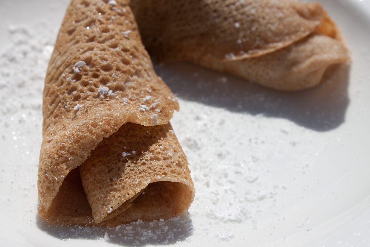 A folded sugar-dusted crêpe on a white plate