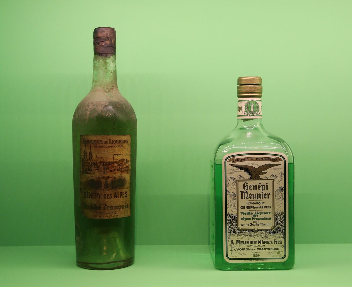 Two old bottles of génépi, one labelled Génépi Meunier, against a pale green background
