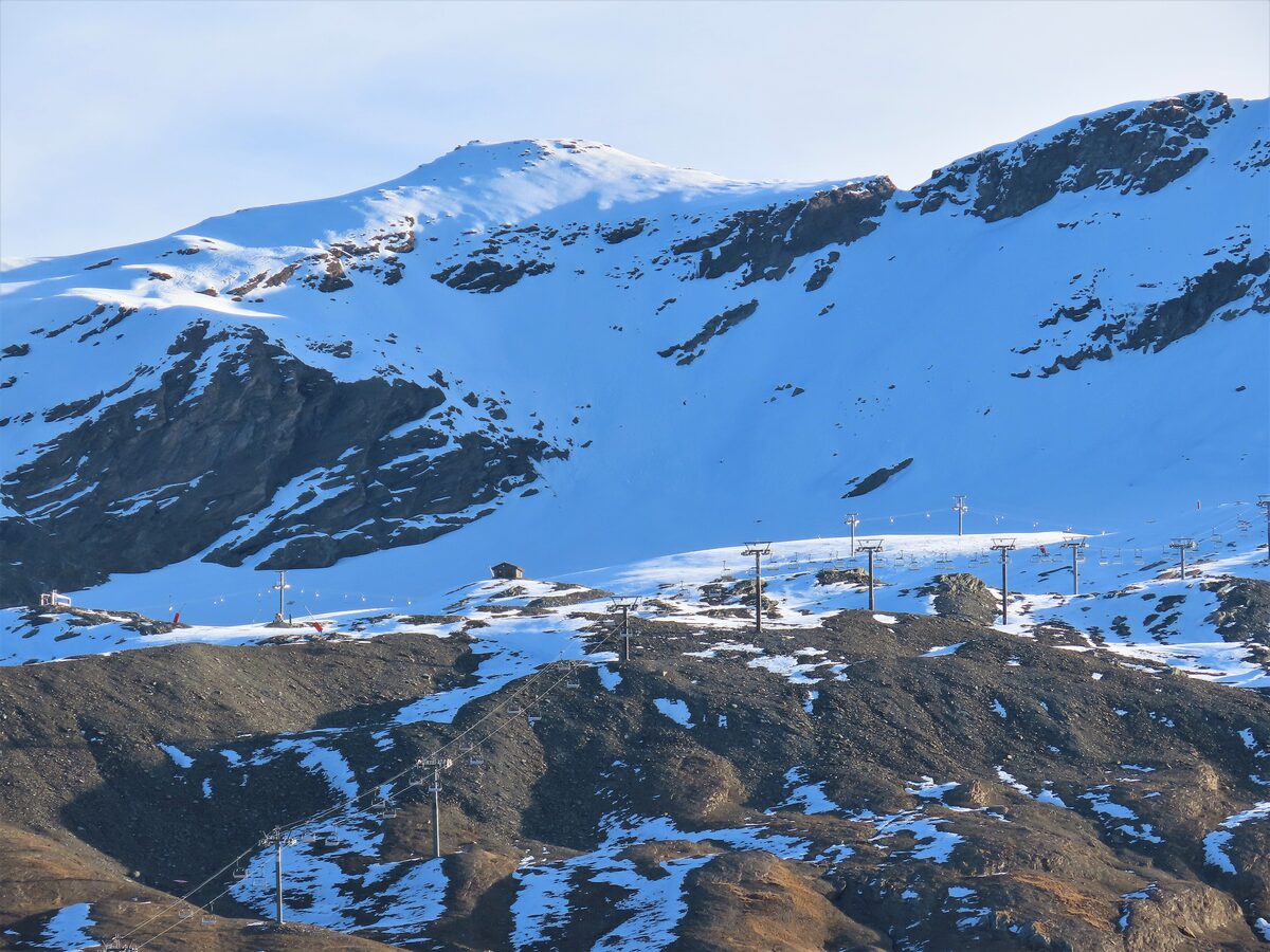 Snow on the Pisaillas glacier above the Iseran pass, with ski lift towers running across the slope below