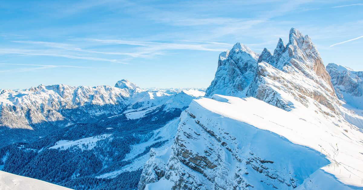 The snow-covered Odle peaks and the Seceda ridge in winter, with the forested valleys of Val Gardena far below
