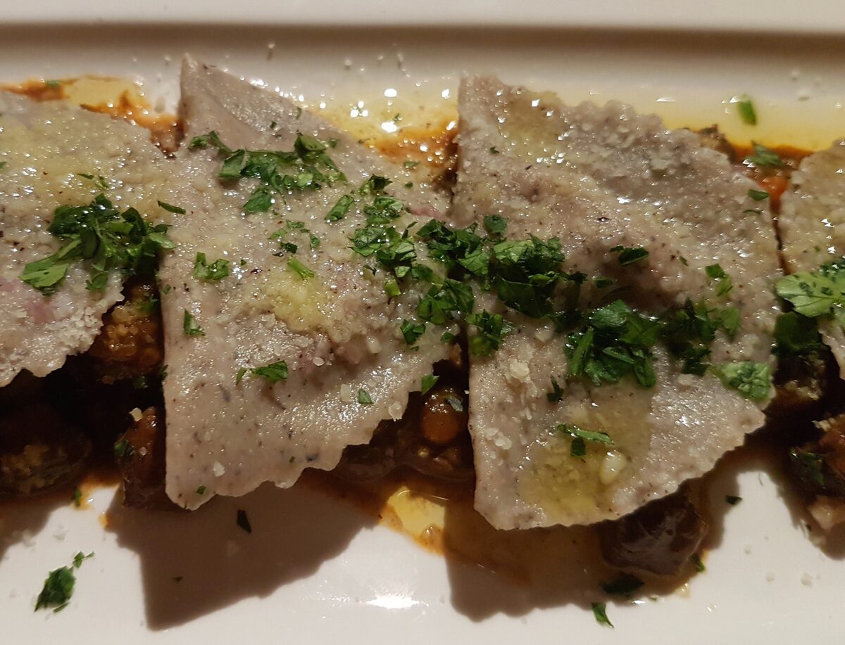 Half-moon buckwheat pasta, the South Tyrolean Schlutzkrapfen, with melted butter and parsley on a venison stew