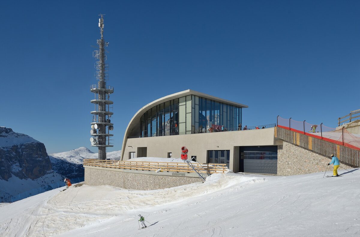 The Dantercepies top station in winter, with its mast and the terrace, and a skier on the snow outside