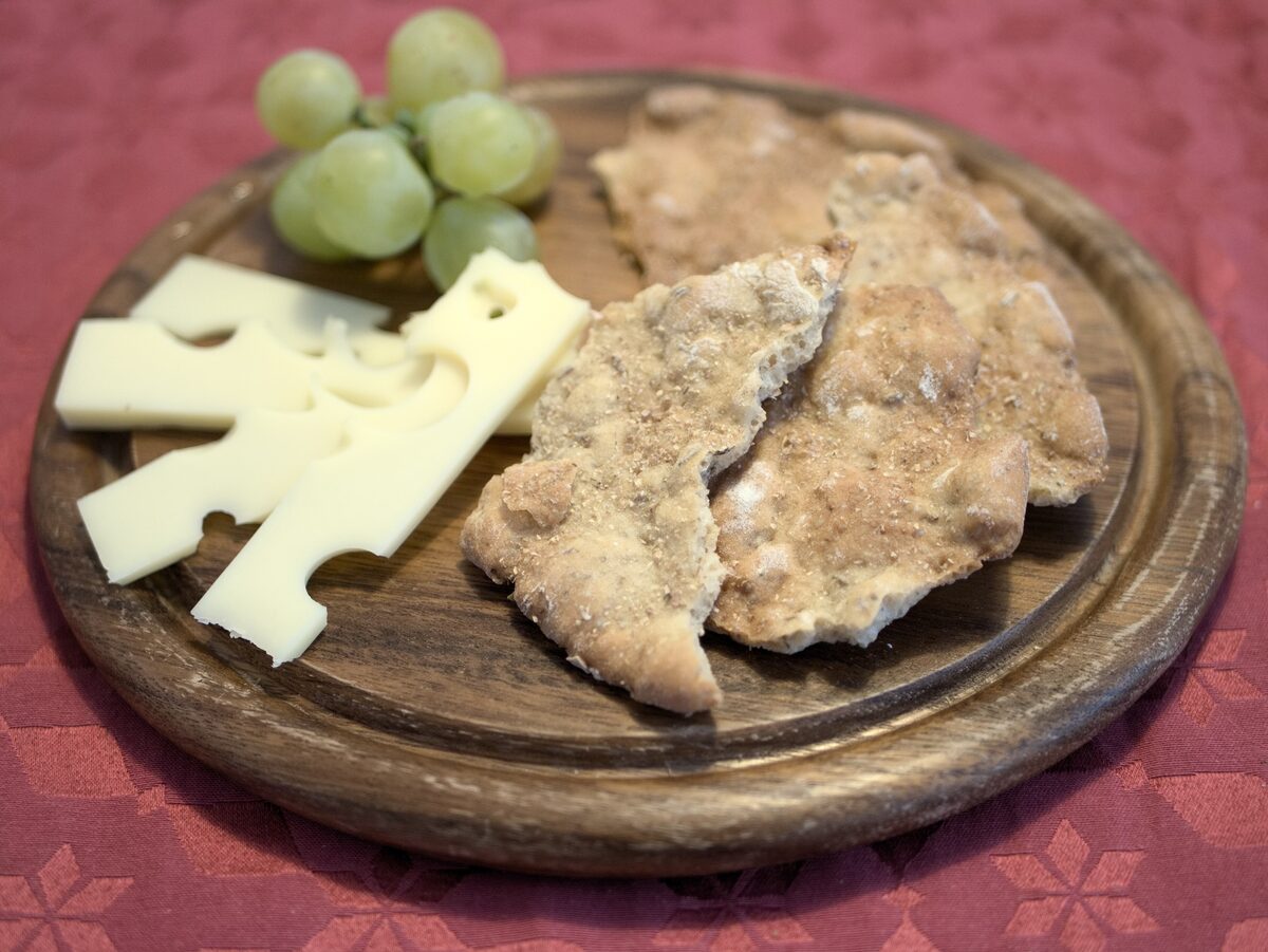 Schüttelbrot, the thin crisp rye bread, with cheese and grapes on a wooden board