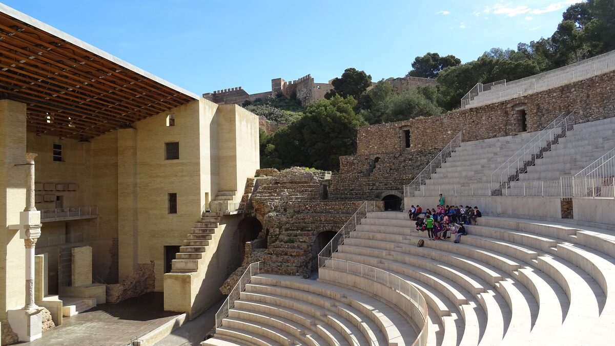 The restored Roman theater of Sagunto with its stone seats and stage building, and the castle on the hill above