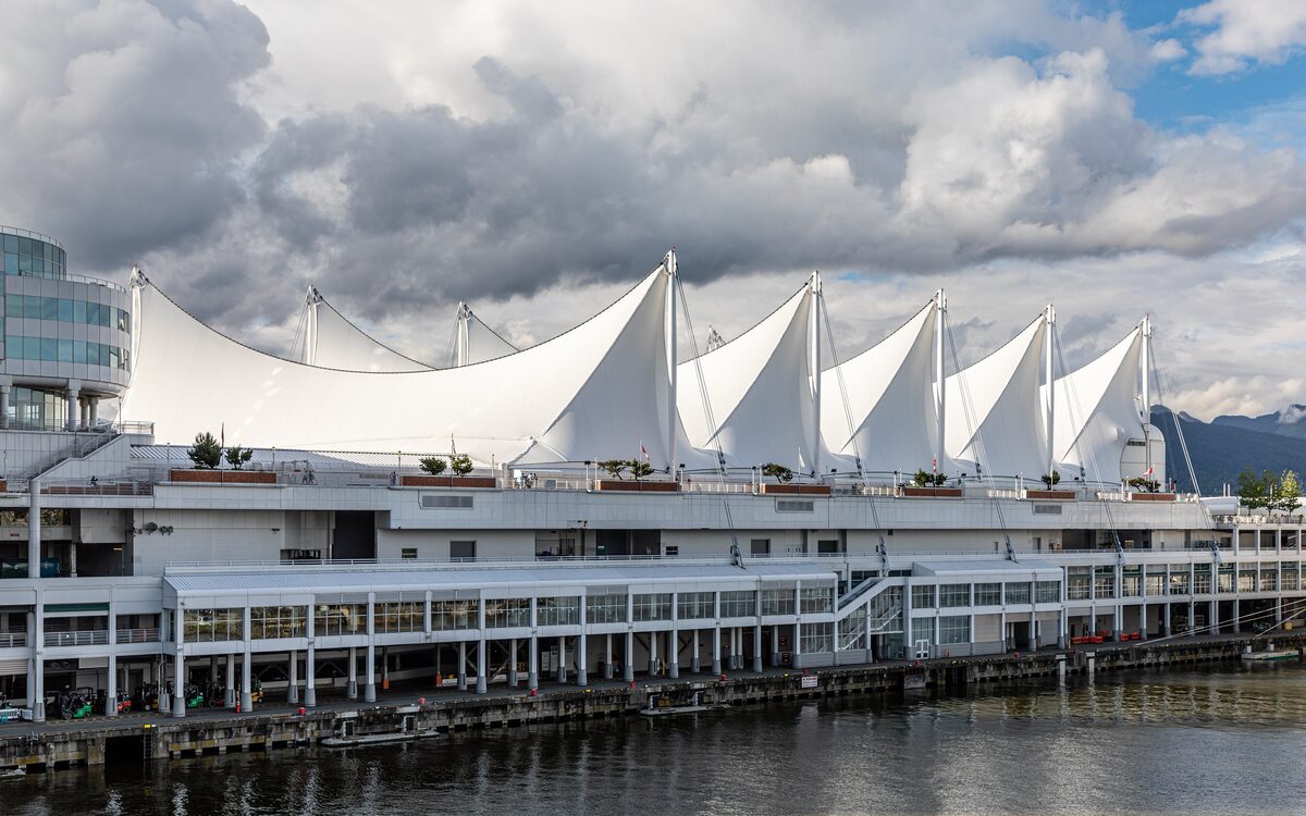 The white sail roofs of Canada Place above the waterfront promenade under a cloudy sky