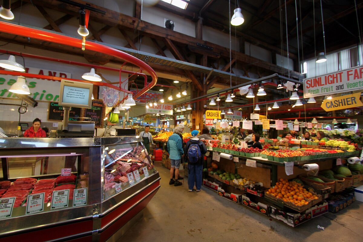 Inside the Granville Island Public Market, with a butcher counter and stalls piled with fruit and vegetables