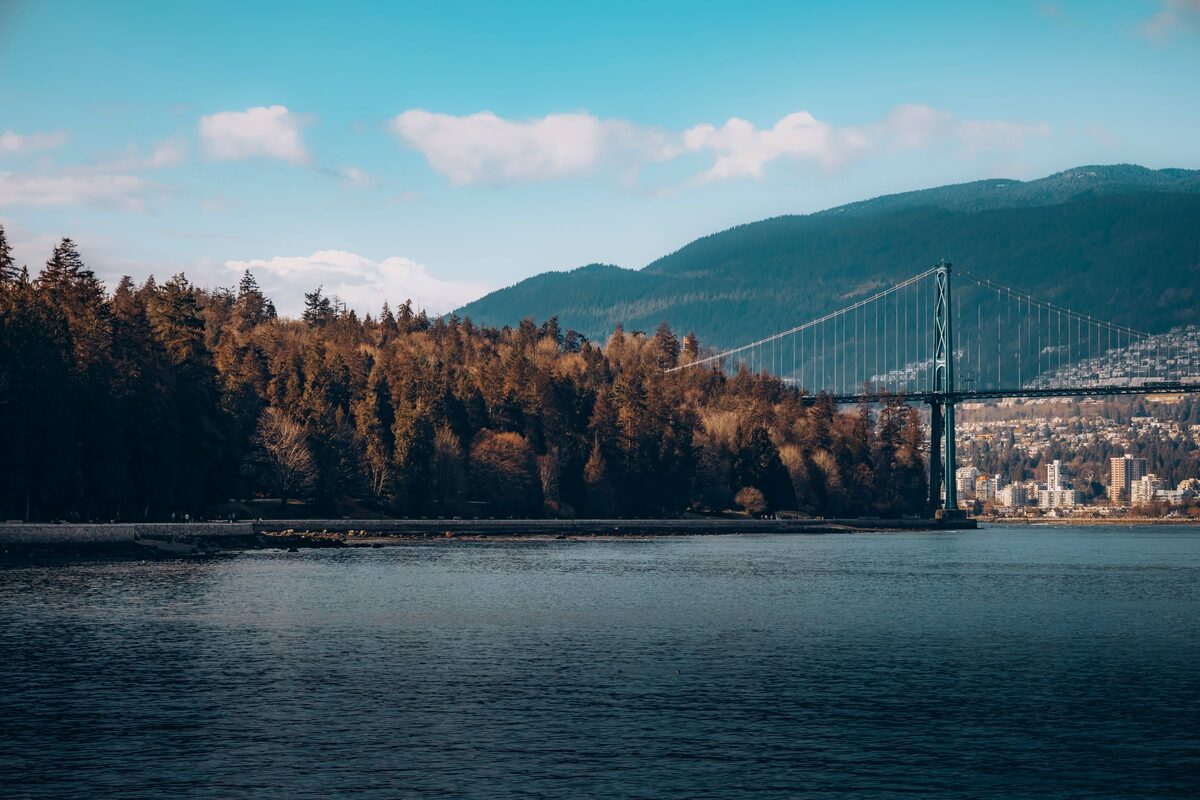 The Lions Gate Bridge crossing the inlet beyond the forested edge of Stanley Park, with the North Shore mountains behind