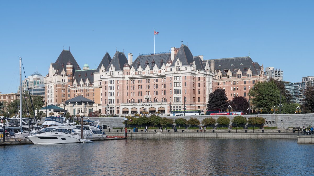The Empress hotel facing Victoria's Inner Harbour, with moored boats in the foreground under a clear sky