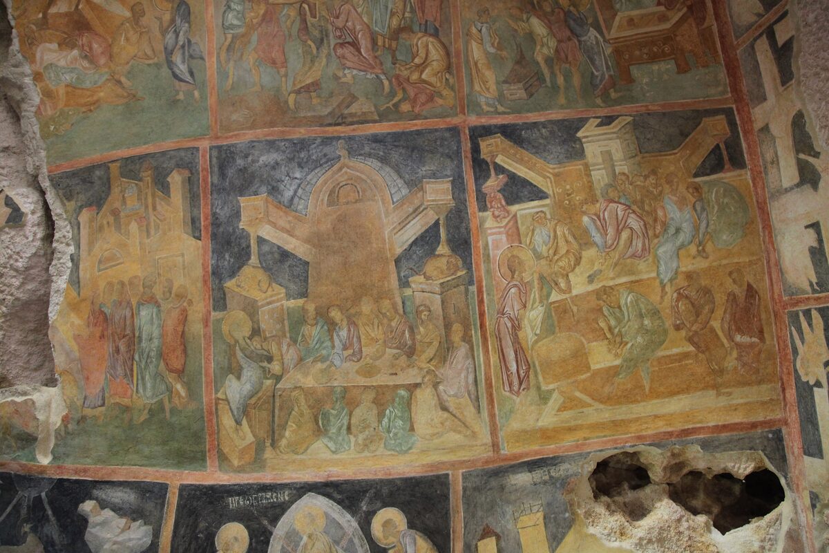 Fourteenth-century frescoes of Gospel scenes in rows of framed panels on the rock walls of a cave church at Ivanovo.