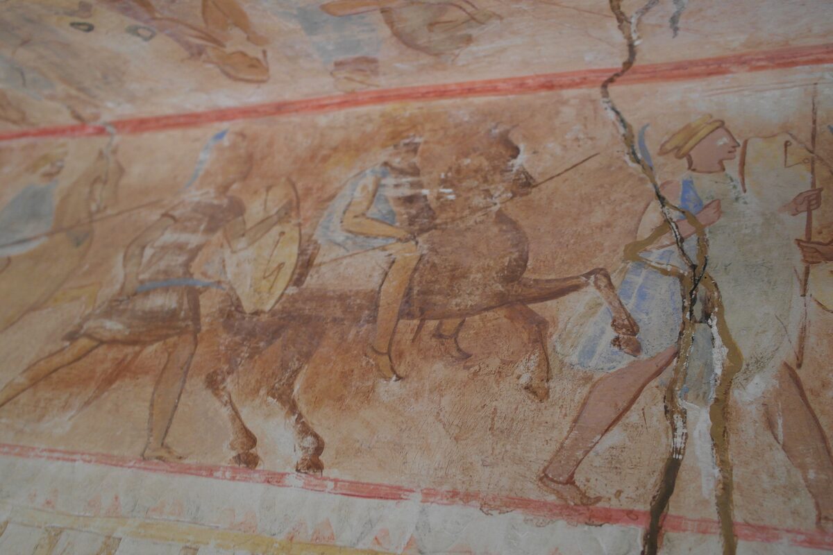 A painted frieze of Thracian warriors with shields and spears and a horseman, from the Thracian tomb of Kazanlak, in soft ochre and blue tones.