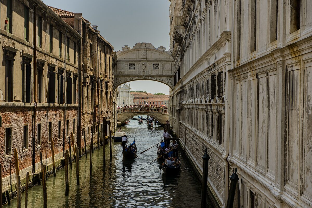 The white stone Bridge of Sighs over a narrow canal between the Doge's Palace and the prisons, with gondolas passing underneath