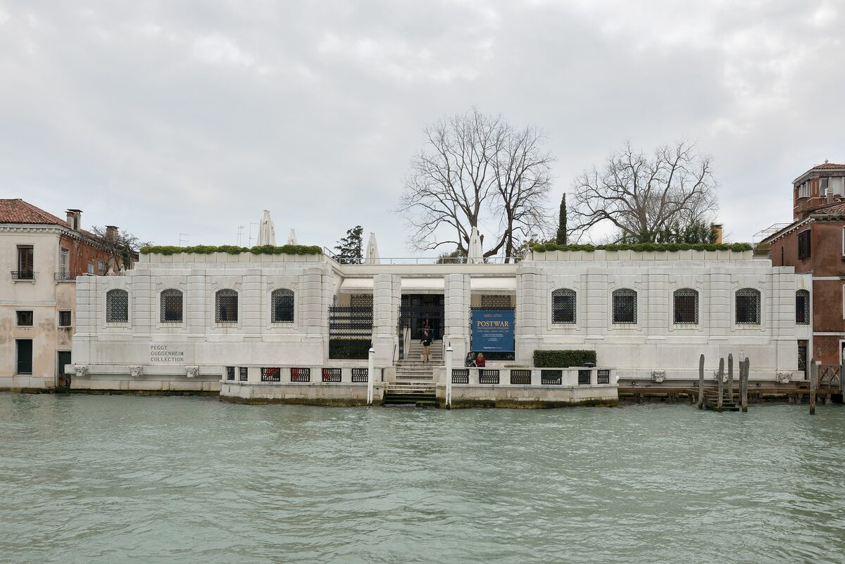 The low, unfinished white marble palace of Palazzo Venier dei Leoni on the Grand Canal, with trees growing from its roof garden