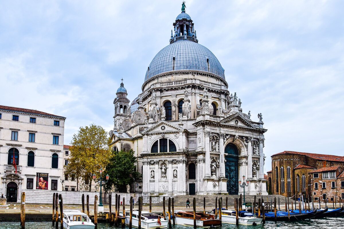 The white domed baroque church of Santa Maria della Salute with its great scrolls, seen from the water with boats moored in front
