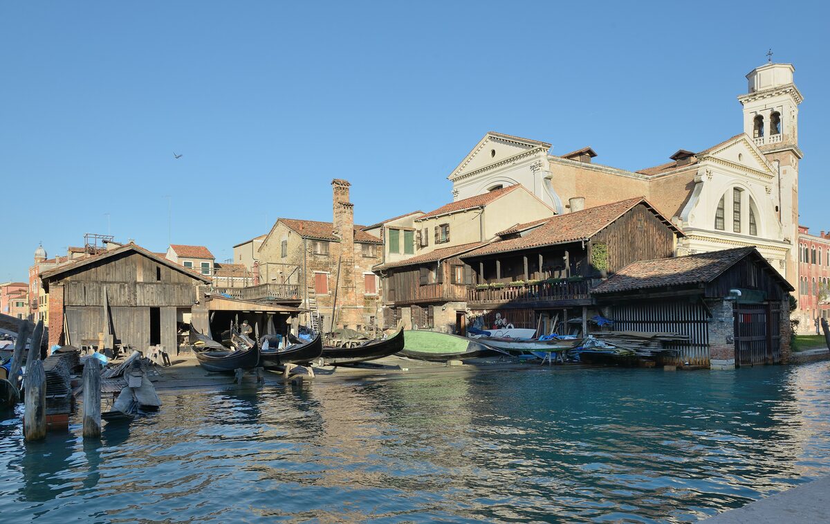 The Squero di San Trovaso, a gondola boatyard with wooden sheds and gondolas pulled up on the slipway, beside a canal with the church of San Trovaso behind