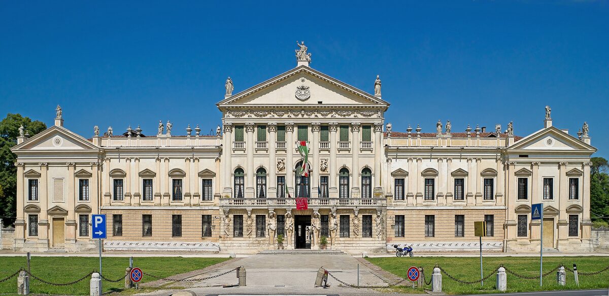 The long classical facade of Villa Pisani at Stra, with statues on the roof and a lawn in front