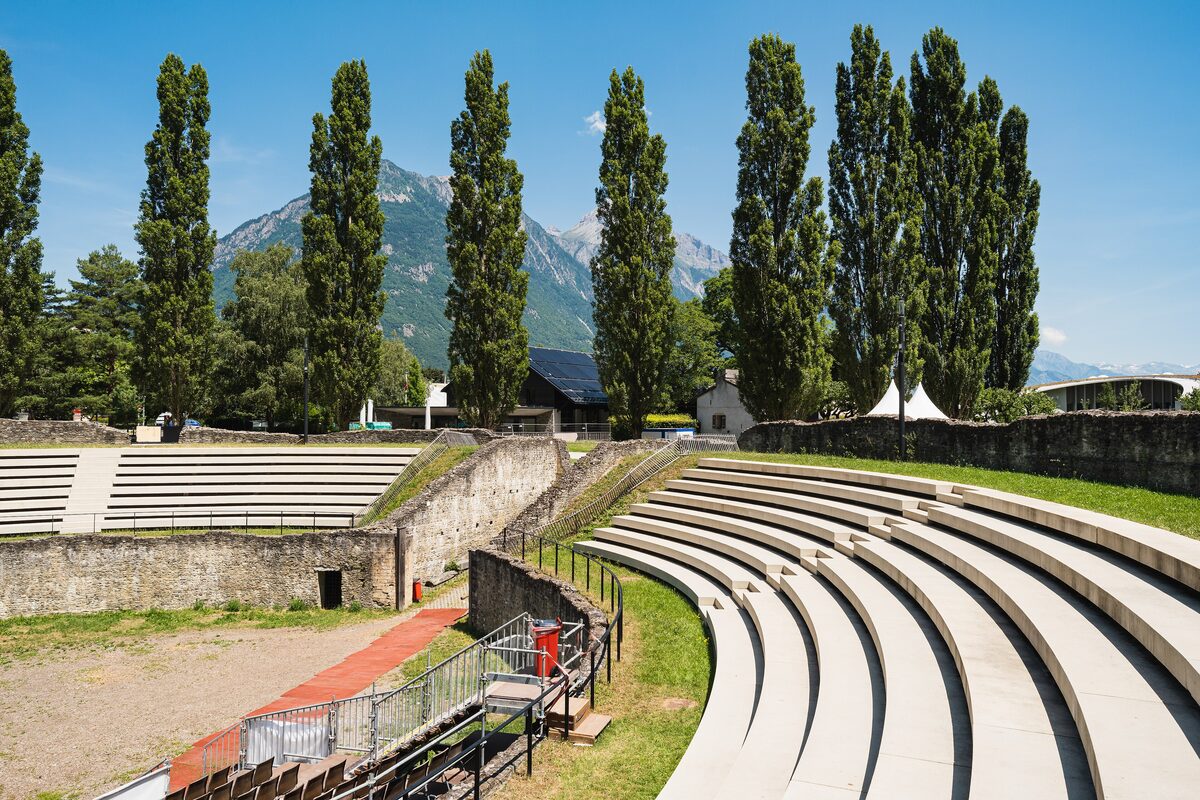 The Roman amphitheatre of Martigny, with curved stone tiers and tall poplars behind