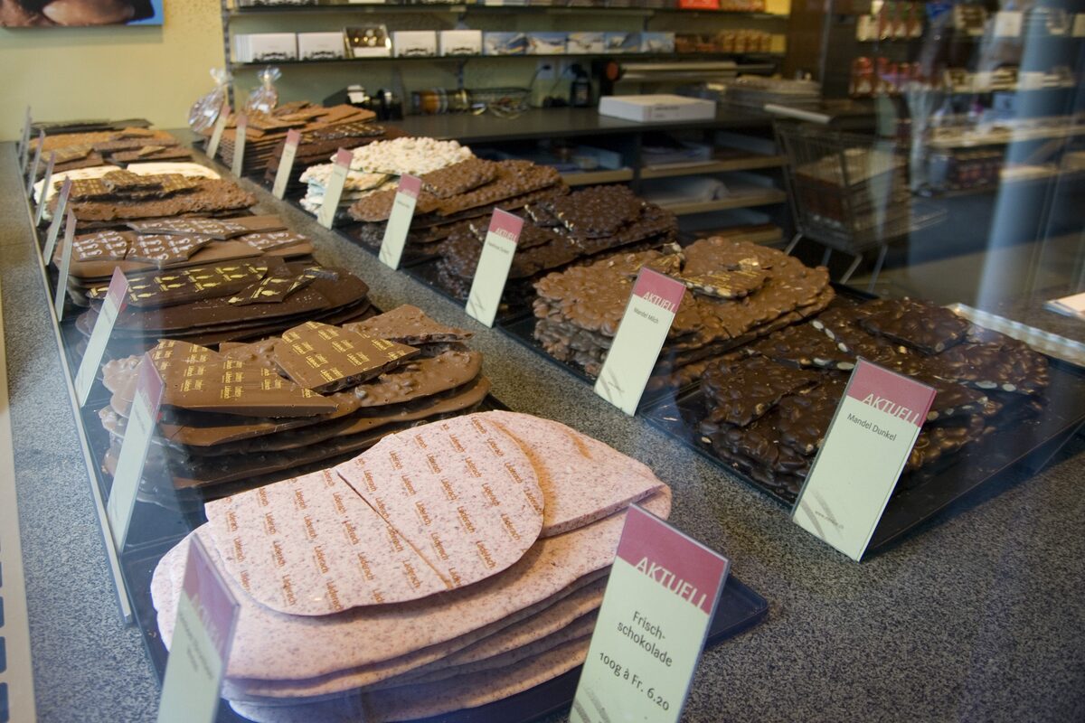 A chocolate shop counter in Interlaken with fresh slabs of dark, milk and pink chocolate, each with a price card